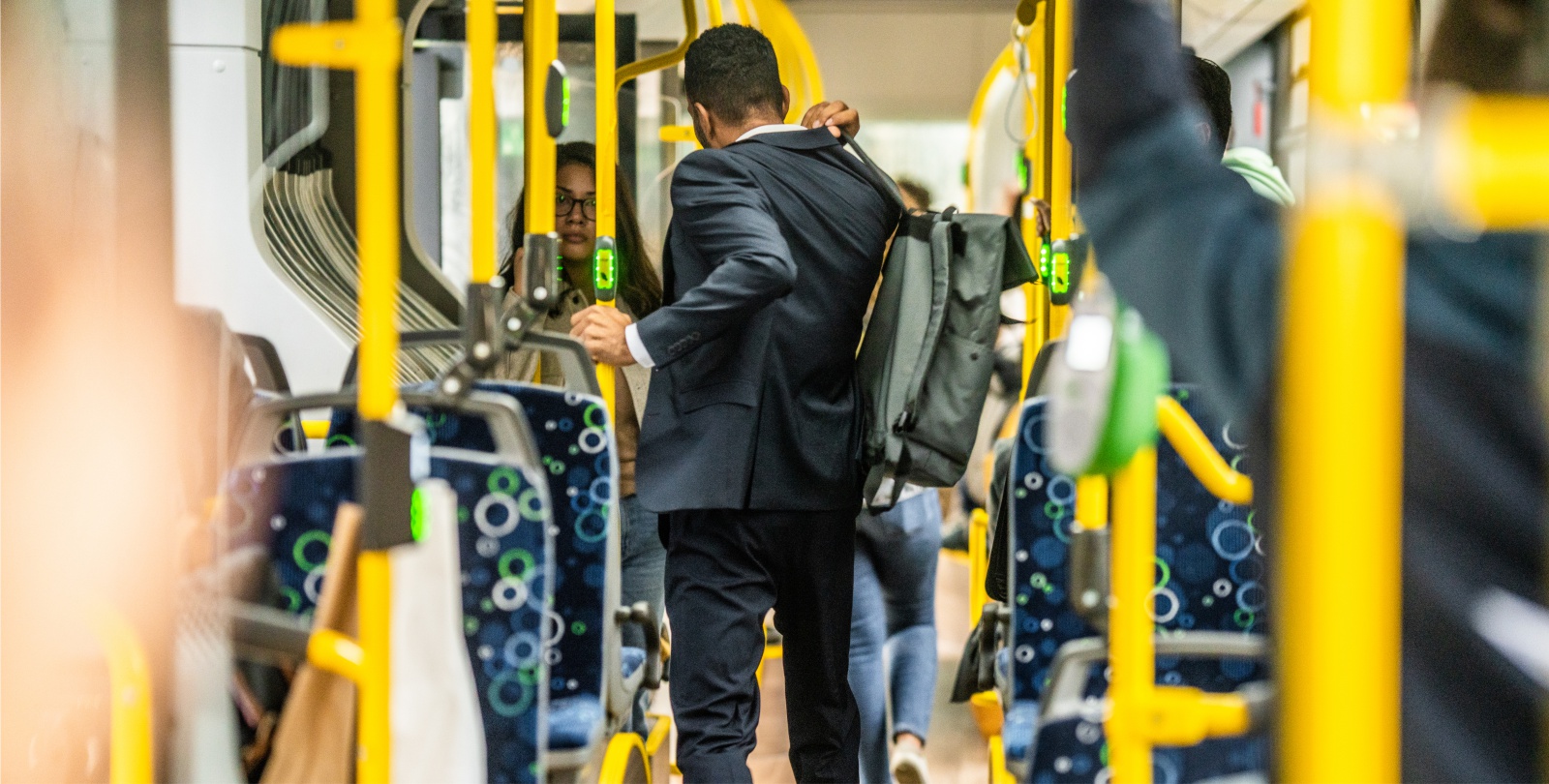 Ein Mann mit Rucksack im Anzug steht mit dem Rcken zum Betrachter im Bus