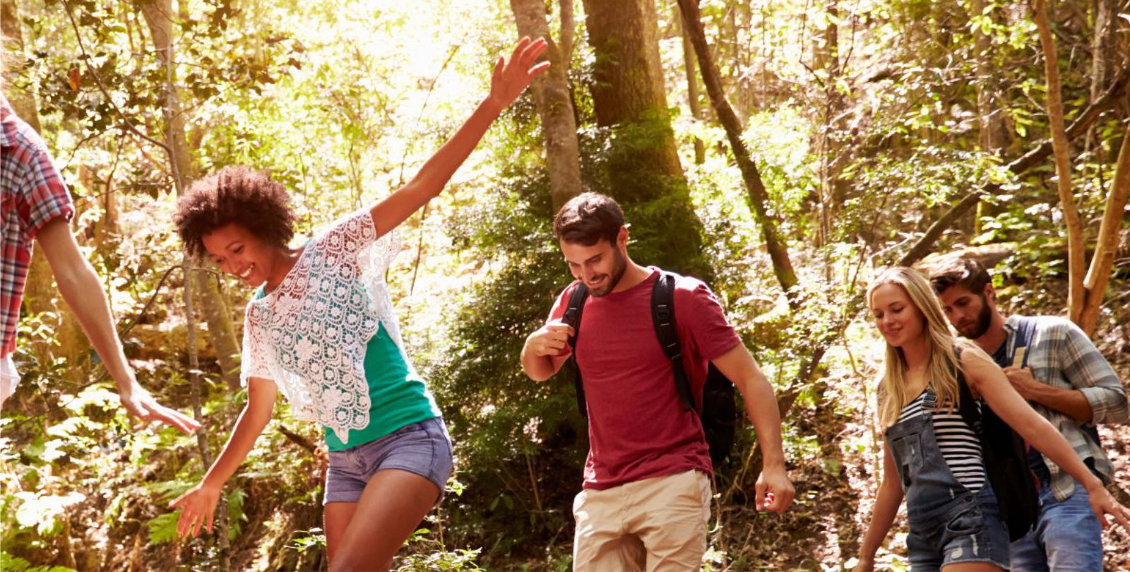 Eine Gruppe wandert gemeinsam auf einem schmalen Waldweg