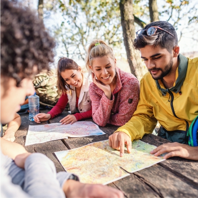 Gruppe sitzt drau�en am Tisch und l�st ein R�tsel