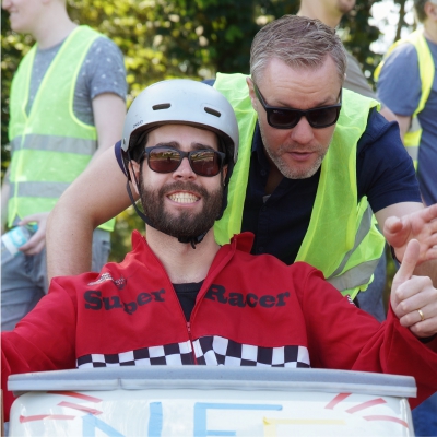 Seifenkistenrennen - jemand schiebt eine Frau mit ihrer Seifenkiste an